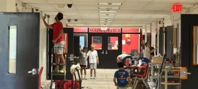 Dads and kids painting and replacing lights along the main building's first-floor hallway